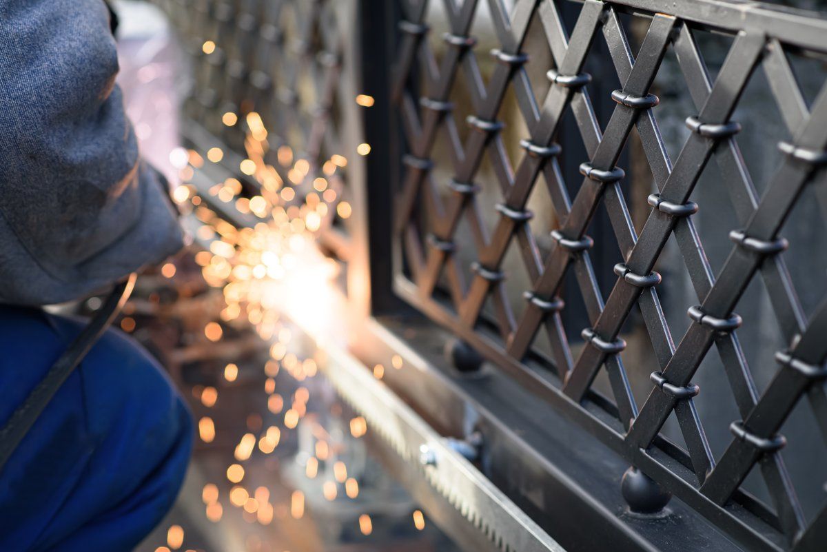 Schweißer arbeitet an einem Metallgitter mit Funkenflug